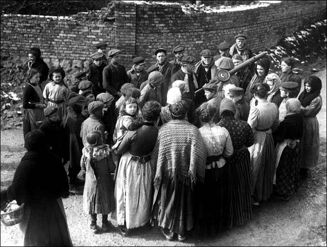 French villagers gathering around a British soldier carrying a machinegun